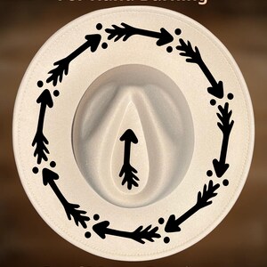 May include: Cream-colored fedora hat with a black arrow design around the brim and a single arrow in the center. The text "For Hand Burning" and "CoolMoonDesigns" are printed on the hat.