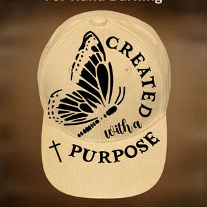 May include: A beige baseball cap with a black butterfly design and the words "CREATED with a PURPOSE". The text "For Hand Burning" and "CoolMoonDesigns" are also visible on the cap.