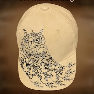May include: A beige baseball cap featuring a black line art illustration of an owl surrounded by flowers and leaves. The text "For Hand Burning" appears at the top, and "CoolMoonDesigns" is printed at the bottom of the cap design.