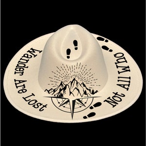 May include: Off-white hat with a wide brim, featuring black text and graphics. The text reads "Wander Are Lost Not All Who", encircling a mountain and compass design. Footprints and a mountain graphic are also present.