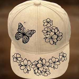 May include: A beige baseball cap featuring black line art designs of a butterfly and floral clusters on the front panels and brim. The text "For Hand Burning" appears at the top and "CoolMoonDesigns" is printed at the bottom of the image.