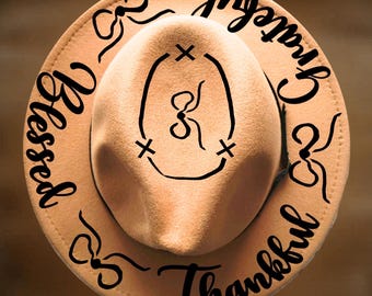 May include: Tan cowboy hat with the words "Blessed", "Grateful", and "Thankful" in black script around the brim. The hat has a central design and the text "For Hand Burning" and "CoolMoonDesigns".