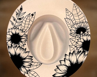 Puede incluir: Un sombrero fedora de color beige con ilustraciones de líneas negras de girasoles y hojas en el ala. El texto For Hand Burning está impreso en la parte superior y CoolMoonDesigns en la parte inferior con una fuente color canela.