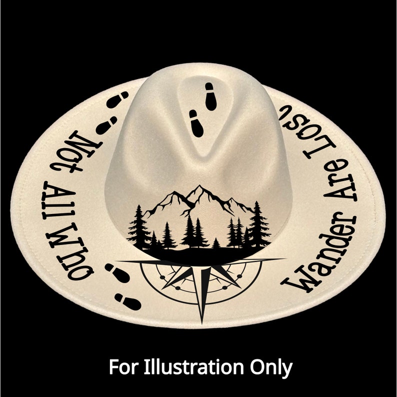 May include: A cream-colored fedora hat with a black mountain and compass design. The hat features the text "Not All Who Wander Are Lost" around the brim and footprints. The hat is a stylish accessory for outdoor enthusiasts.
