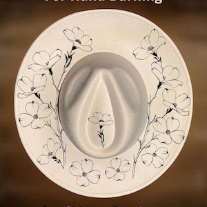 Può includere: Un cappello fedora color crema con disegni a linee nere di fiori bruciati sulla tesa e sulla corona. Il testo "For Hand Burning" appare in alto e "CoolMoonDesigns" in basso con un carattere color marrone chiaro su sfondo scuro.