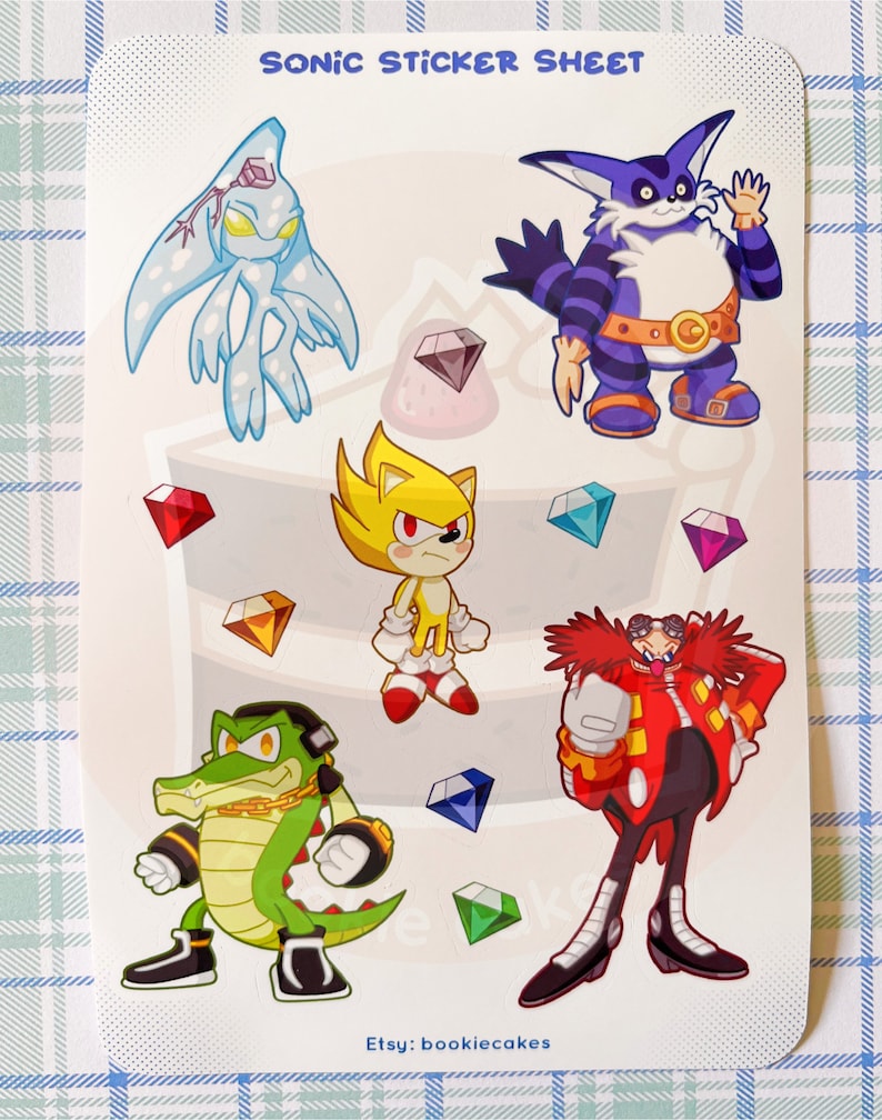 May include: A sticker sheet featuring characters from the Sonic the Hedgehog video game series. The sheet includes Sonic, Knuckles, Tails, Shadow, and Eggman. The characters are depicted in a cartoon style and are surrounded by colorful gems.