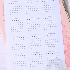 May include: A white sheet of yearly overview planner stickers featuring twelve individual monthly calendar grids from January to December with black text and numbers. The sheet includes the title YEARLY OVERVIEW PLANNER STICKERS and the code YG001 at the top, with the text Etsy@madebybookie at the bottom.