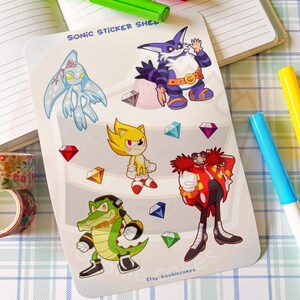 May include: A sheet of stickers featuring characters from the Sonic the Hedgehog video game franchise. The stickers are printed on a white background with a light blue, pink, and green gradient. The characters include Sonic, Knuckles, Tails, Shadow, and Amy. The stickers are all in a cartoon style and are brightly colored. The text "Sonic Sticker Sheet" is printed at the top of the sheet. The text "Etsy: bookiecakes" is printed at the bottom of the sheet.