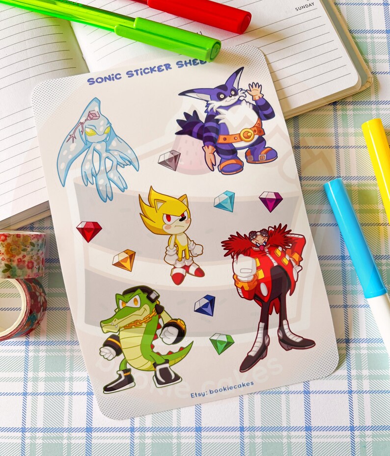 May include: A sheet of stickers featuring characters from the Sonic the Hedgehog video game franchise. The stickers are printed on a white background with a light blue, pink, and green gradient. The characters include Sonic, Knuckles, Tails, Shadow, and Amy. The stickers are all in a cartoon style and are brightly colored. The text "Sonic Sticker Sheet" is printed at the top of the sheet. The text "Etsy: bookiecakes" is printed at the bottom of the sheet.