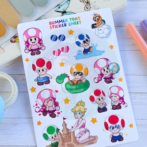 May include: A white sticker sheet titled SUMMER TOAD STICKER SHEET featuring various cartoon characters including Toads in swimsuits, sunglasses, and pool floats, a character on a cloud, and a character building a sandcastle with yellow stars.