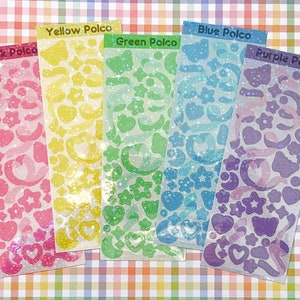 May include: Five sheets of iridescent holographic stickers with different colors and designs. The sheets are labeled "Pink Polco", "Yellow Polco", "Green Polco", "Blue Polco", and "Purple Polco".