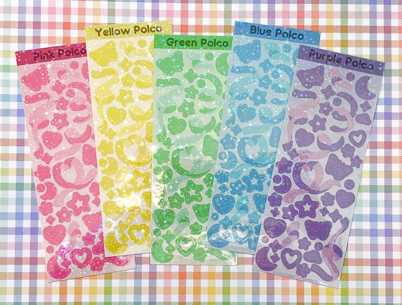 May include: Five sheets of iridescent holographic stickers with different colors and designs. The sheets are labeled "Pink Polco", "Yellow Polco", "Green Polco", "Blue Polco", and "Purple Polco".