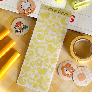 May include: A sheet of yellow glitter stickers with various shapes, including stars, hearts, moons, and butterflies. The sheet is labeled "Yellow Polco".