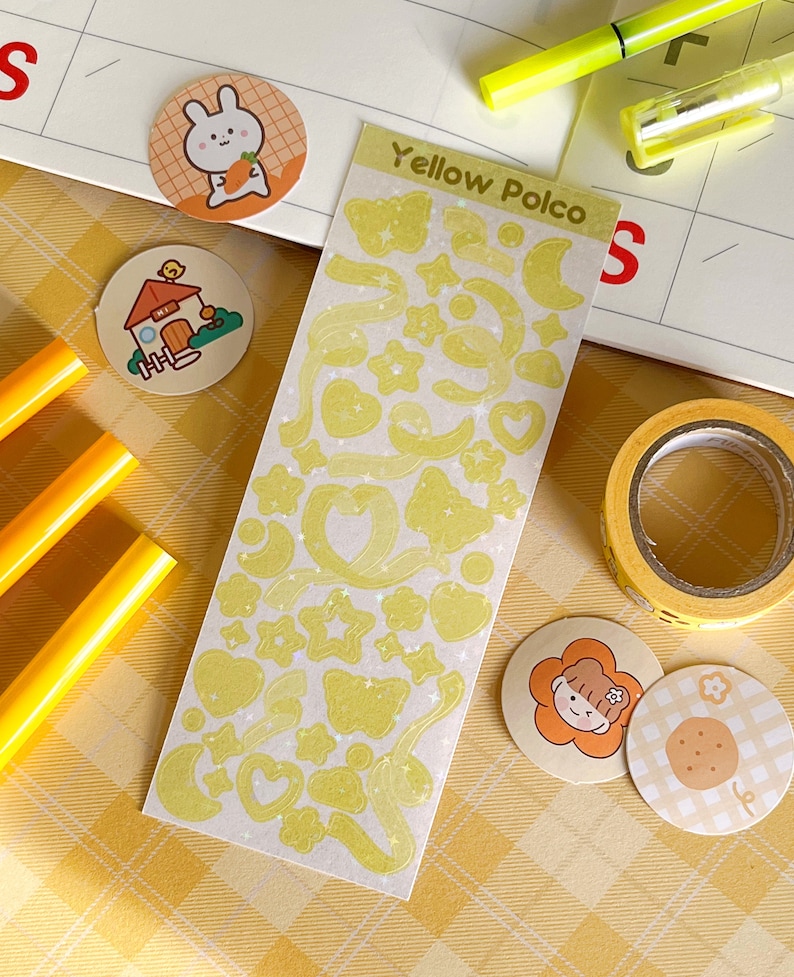 May include: A sheet of yellow glitter stickers with various shapes, including stars, hearts, moons, and butterflies. The sheet is labeled "Yellow Polco".