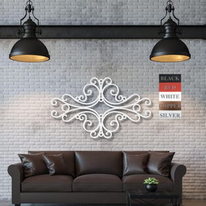 May include: White metal wall decor with a decorative scroll design. The decor is mounted on a white brick wall above a brown leather sofa. The decor is available in black, red, white, copper, and silver.