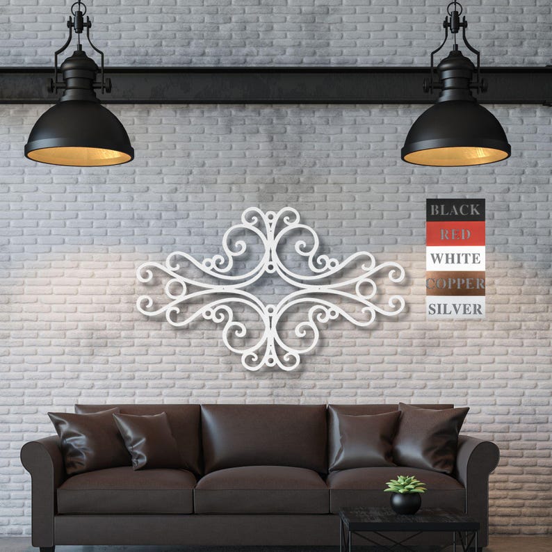 May include: White metal wall decor with a decorative scroll design. The decor is mounted on a white brick wall above a brown leather sofa. The decor is available in black, red, white, copper, and silver.