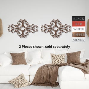 May include: Two decorative metal wall decor pieces in a scrolled design. The pieces are shown in a copper finish. The text "2 Pieces shown, sold separately" is below the decor.