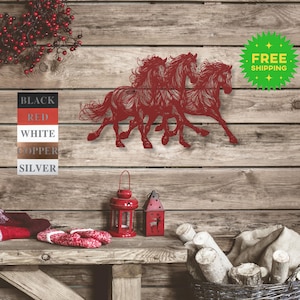 May include: Metal wall art featuring three horses running side by side. The horses are cut out of metal and painted red. The art is mounted on a wooden wall.