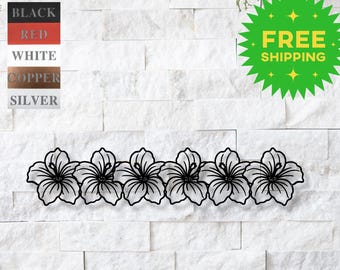 May include: A row of six black hibiscus flowers in a continuous line, against a white brick wall background.