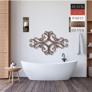 May include: A brown metal wall decor with a scroll design, hanging above a white bathtub in a bathroom. The wall decor is in the shape of a cross with four scrolls on each side. The bathroom has a white tiled floor and a white wall with a small candle holder on the wall.