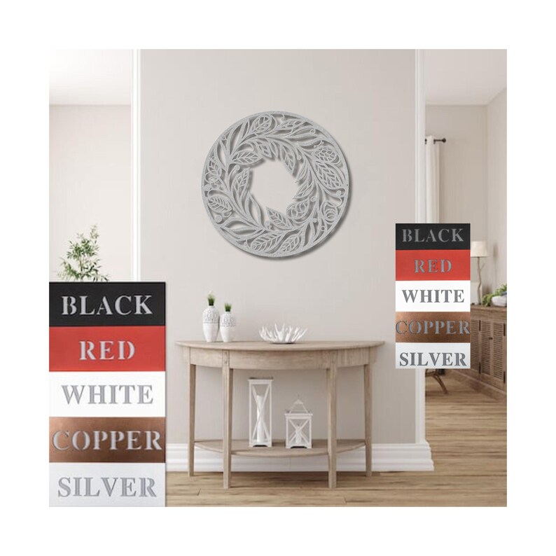 May include: A white, round, decorative wall hanging with a floral design. The wall hanging is mounted on a white wall in a room with a wooden floor. The wall hanging is available in black, red, white, copper, and silver.