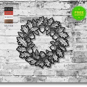 May include: A black metal wreath featuring an oak leaf and acorn design. The wreath is circular and has intricate cut-out details. The background is a white brick wall. A green "FREE SHIPPING" sticker is in the upper right corner.