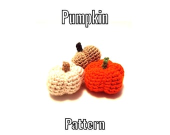 Może przedstawiać: Trzy małe szydełkowane dynie w kolorze białym, beżowym i pomarańczowym, każda z krótką łodyżką na górze. Tekst "Pumpkin" znajduje się nad przedmiotami, a słowo "Pattern" jest wydrukowane poniżej, wszystko na jednolitym białym tle.