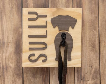 Puede incluir: Porta-correas de perro de madera con el nombre "Sully" y una silueta de la parte trasera de un perro con un gancho para colgar una correa.