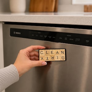 May include: A rectangular dishwasher magnet featuring ten light wood tiles arranged in two rows. The top row spells CLEAN in black letters, while the bottom row spells DIRTY in black letters, with the text oriented upside down for rotation.