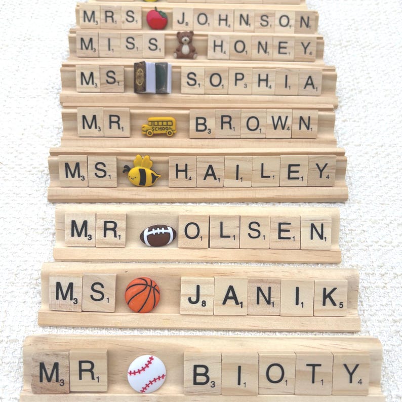 Personalized Scrabble tile name plate for teachers and coaches with cute embellishments like apples, buses, bees, sports balls, and books. A unique classroom desk name sign or gift for teacher appreciation, back-to-school, or end-of-year.