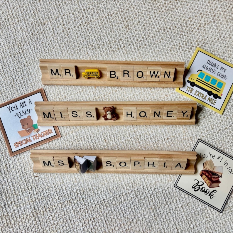 Handmade Scrabble tile name plate with custom names and decorative charms including apple, bus, bee, sports balls, and more. A fun, unique teacher desk accessory or coach gift, ideal for back-to-school or end-of-year presents.