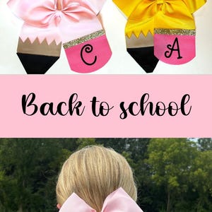 May include: A set of four personalised pencil hair bows in pink, yellow, and purple. Each bow features a black and white pencil design with a gold glitter accent and a pink letter.