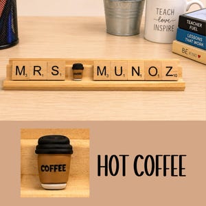 Op de afbeelding: Een licht houten displayrek met beige lettertegels die MRS. MUNOZ spellen, gescheiden door een miniatuur bruin en zwart koffiekopje met het woord COFFEE erop gedrukt. De tegels bevatten zwarte letters en kleine numerieke subscripten.