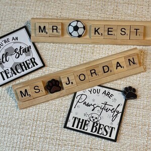 Handmade Scrabble tile name plate with custom names and decorative charms including apple, bus, bee, sports balls, and more. A fun, unique teacher desk accessory or coach gift, ideal for back-to-school or end-of-year presents.
