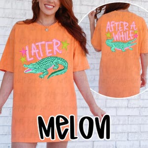 May include: Orange t-shirt with a green alligator graphic and the text "LATER" on the front. The back of the shirt features the text "AFTER A WHILE" and a matching alligator. The word "MELON" is at the bottom of the shirt.