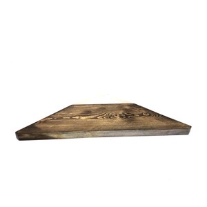 Op de afbeelding: Een donkerbruin houten plank met een driehoekige vorm. De plank is gemaakt van natuurlijk hout met zichtbare nerven.