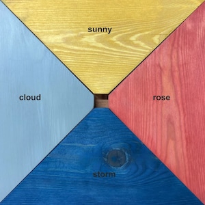 May include: Four wooden squares painted in different colors: sunny yellow, cloud blue, storm blue, and rose red. The squares are arranged in a diamond shape with the words "sunny", "cloud", "storm", and "rose" written in black.