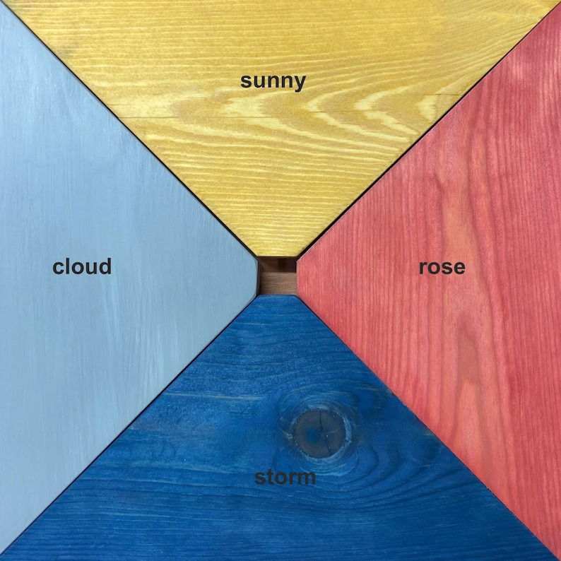 May include: Four wooden squares painted in different colors: sunny yellow, cloud blue, storm blue, and rose red. The squares are arranged in a diamond shape with the words "sunny", "cloud", "storm", and "rose" written in black.