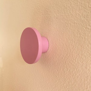 Puede incluir: Un pomo de madera rosa montado en una pared.