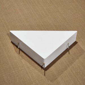 May include: White triangular shelf with three metal nails protruding from the bottom.