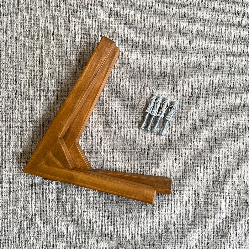 May include: A set of four brown wooden corner brackets with four silver wall anchors.