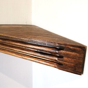 May include: A dark brown wooden corner shelf with a decorative edge. The shelf is made of solid wood and has a natural finish.