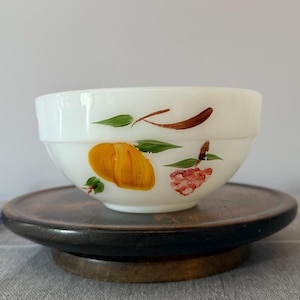 May include: White milk glass bowl with a hand-painted design of fruit and flowers. The bowl has a scalloped rim and is perfect for serving snacks or desserts.
