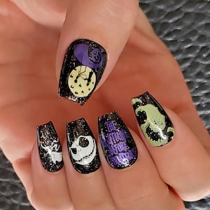 May include: Black and green nail polish with a glittery finish. The nails feature images from the film "The Nightmare Before Christmas".