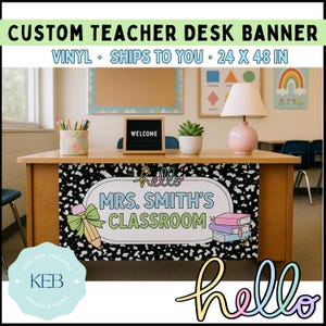 May include: A custom teacher desk banner with the text "MRS. SMITH'S CLASSROOM" in a classroom setting. The banner is 48 inches wide and 24 inches tall, with a black and white speckled background and colorful accents.