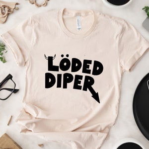 May include: A beige t-shirt with a black graphic that says "LÖDED DIPER" with a small arrow pointing to the right.