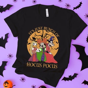 Könnte beinhalten: Schwarzes T-Shirt mit einer Grafik im Vintage-Stil von Mickey Mouse, Donald Duck und Goofy, die als Hexen verkleidet sind. Die Grafik enthält den Text "It's Just a Bunch of Hocus Pocus".