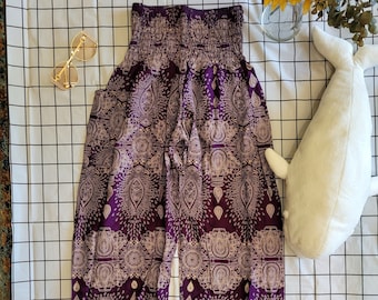 May include: Purple harem pants with a beige paisley pattern. The pants have a gathered elastic waistband and ankles. A pair of gold-rimmed sunglasses and a stuffed whale are also in the image.