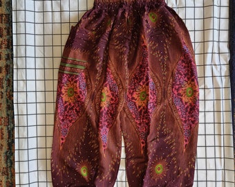 May include: Brown, pink, and green patterned pants with an elastic waistband. The pants have a loose, flowing fit and are made of a soft, lightweight fabric.
