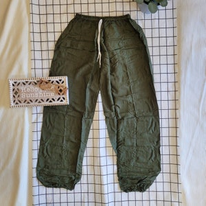 May include: A pair of dark green, loose-fitting pants with a drawstring waist and elastic cuffs.